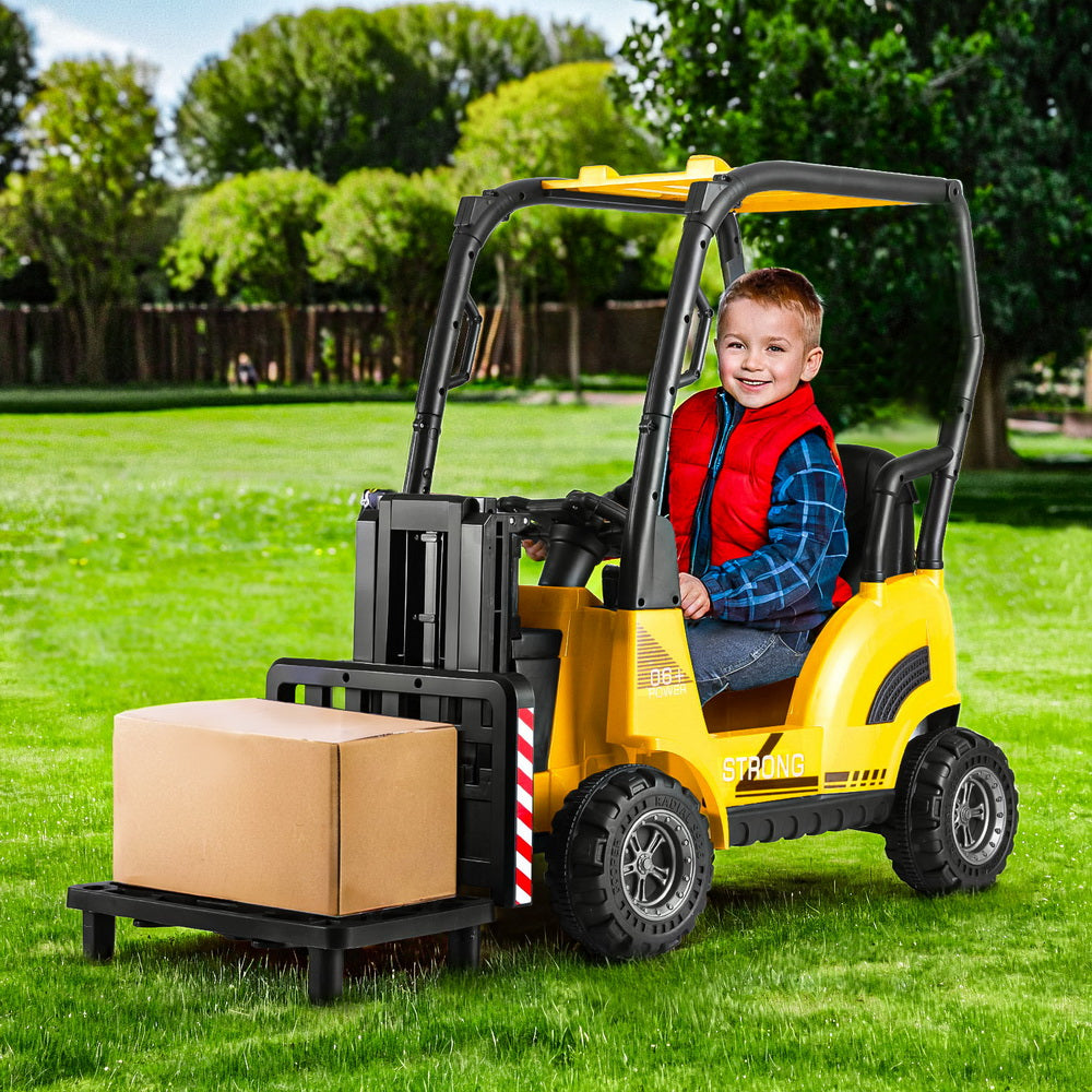Child playing with a toy forklift in a grassy outdoor area